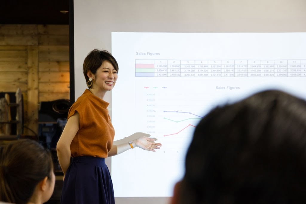 Japanese businesswoman standing by projection screen, giving presentation Japanese businesswoman standing by projection screen, giving presentation