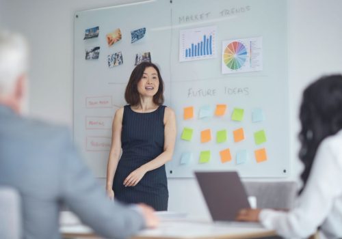 609e3c9dc8d51 Mature businesswoman giving presentation to colleagues. Male and female professionals are planning strategy at board room. They are working at office.