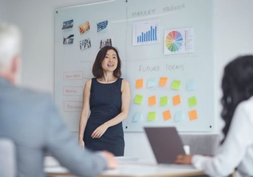 609e3c9dc8d51 Mature businesswoman giving presentation to colleagues. Male and female professionals are planning strategy at board room. They are working at office.
