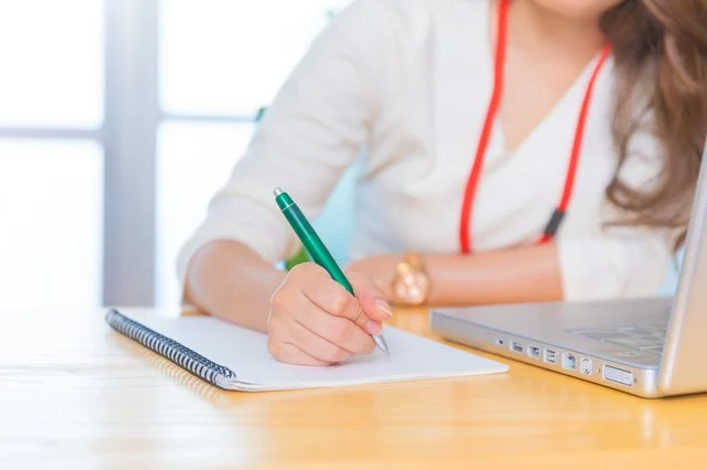 ノートにメモする女性